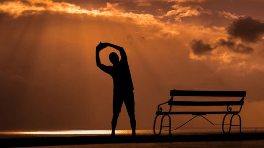 Man stretching at sunrise by the ocean, symbolizing healthy habits to improve male fertility naturally.