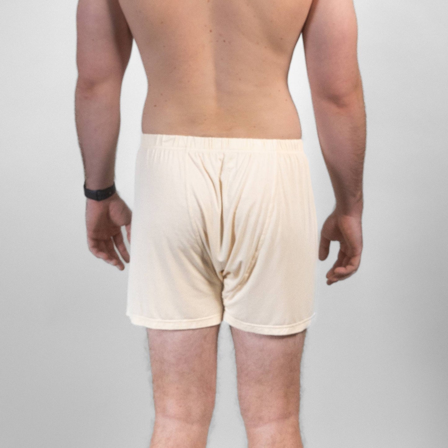 Male model wearing beige bamboo Lyocell boxer shorts, back view showcasing fabric fit and drape.