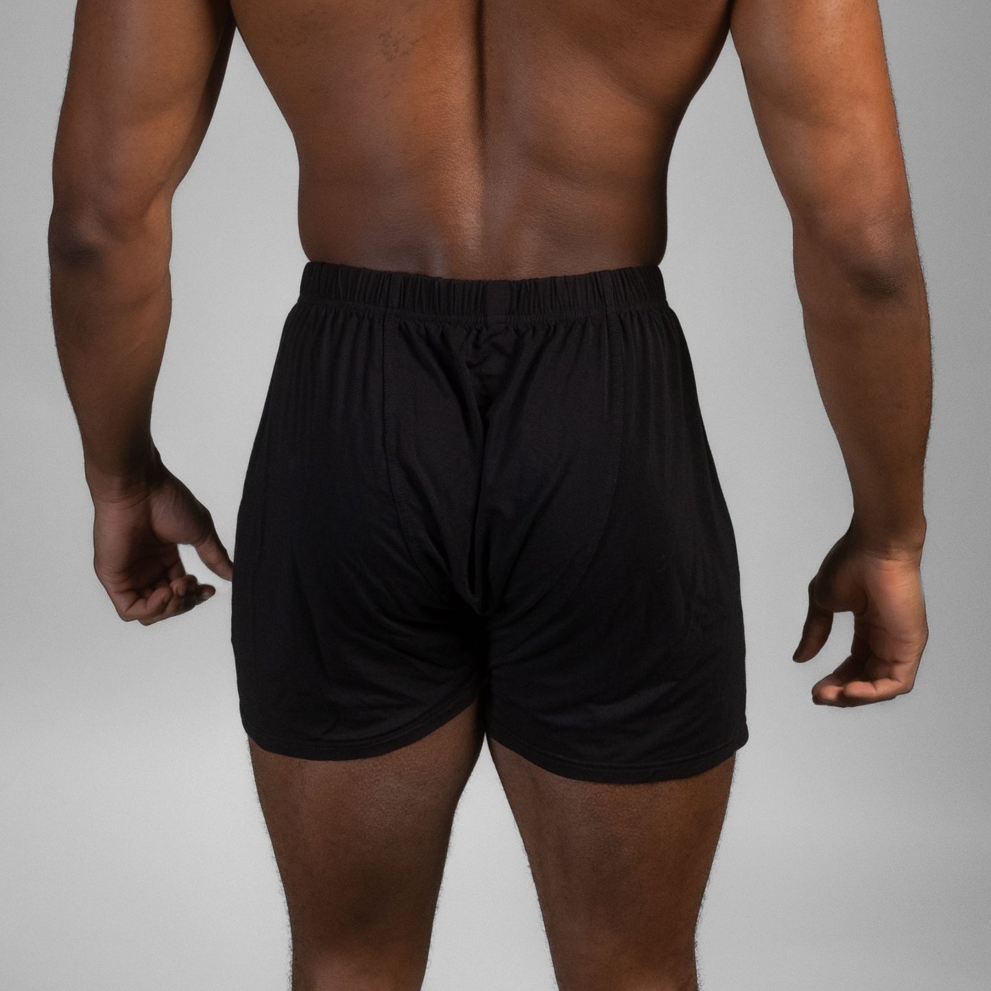 Rear view of male model wearing black Mr. Fertyl bamboo Lyocell boxers designed for breathability and fertility safety.