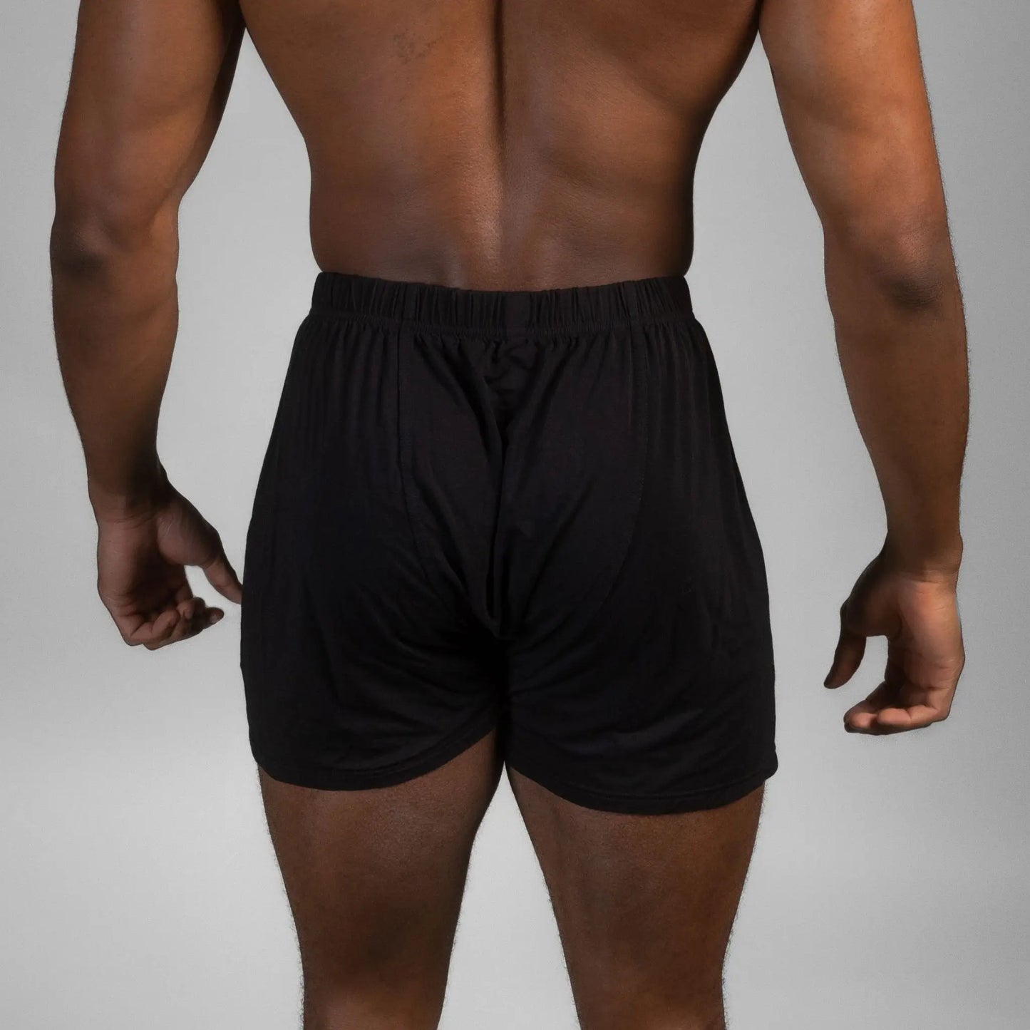 Rear view of male model wearing black Mr. Fertyl bamboo Lyocell boxers designed for breathability and fertility safety.