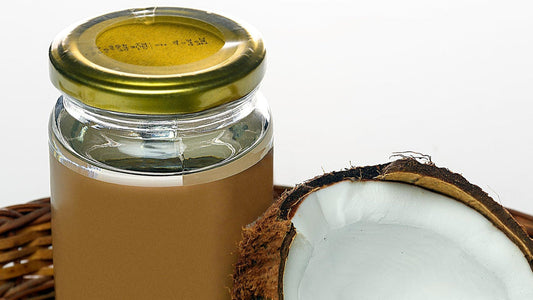 Coconut oil in jar and halved coconut used as natural oil-based lube alternative safe for fertility and sensitive skin.