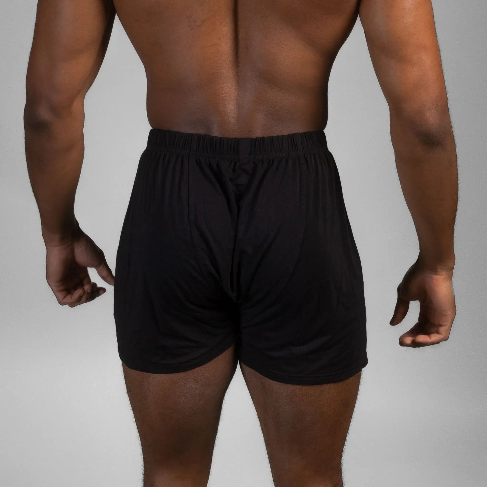 Rear view of male model wearing black Mr. Fertyl bamboo Lyocell boxers designed for breathability and fertility safety.